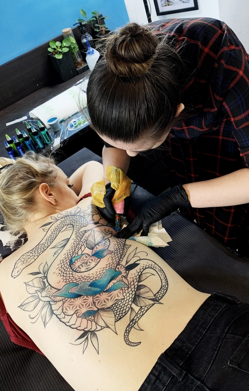 Osoba tatuująca węża na plecach