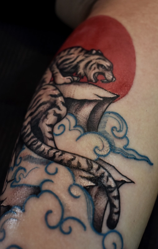 Tatuaż tygrysa na skarpie w chmurach
